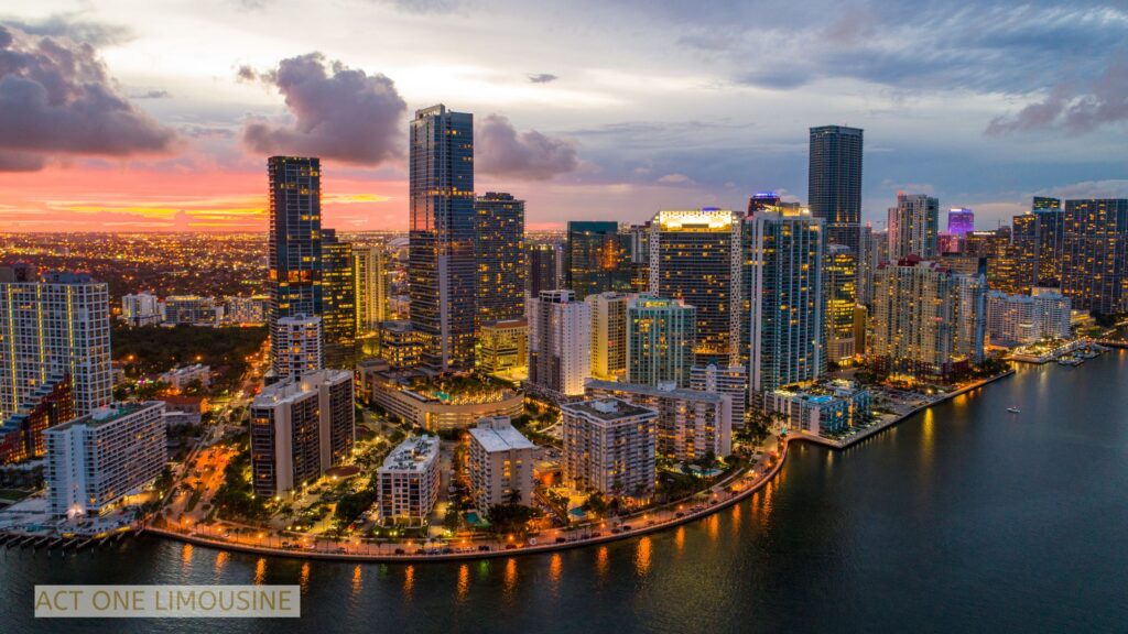 Aerial view of downtown Miami showcasing modern skyscrapers, waterfront high-rises, and the shimmering Biscayne Bay under a clear South Florida sky.